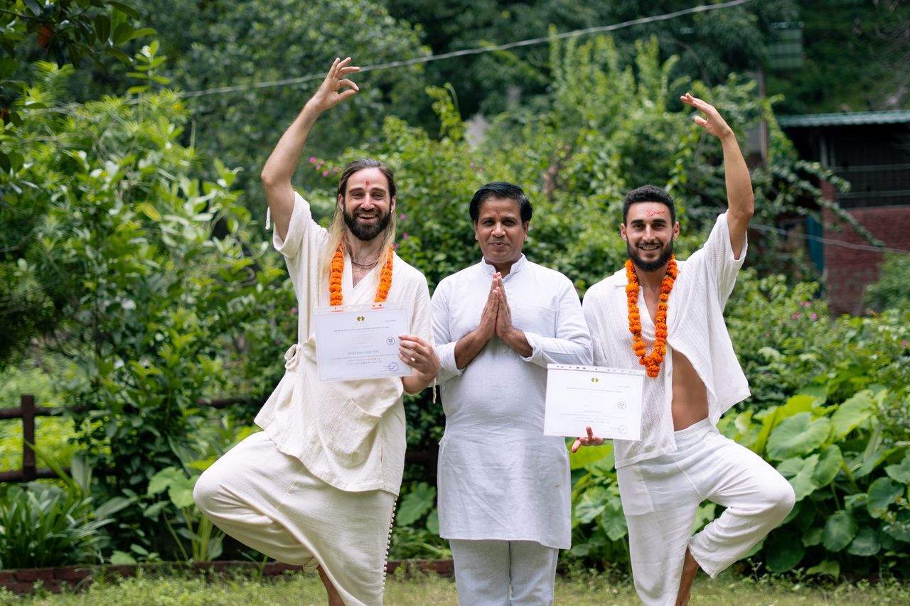 About Yoga graduates celebrating certification with instructor in Rishikesh, India.
